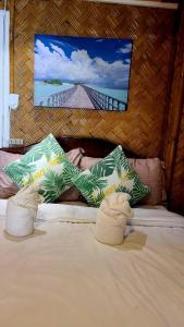 uma cama com duas almofadas verdes e brancas em Coconut Cottages El Nido em El Nido