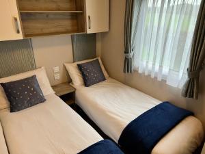 two beds in a small room with a window at 3 Bedroom Caravan MC37, Shanklin, Isle of Wight in Shanklin +15 photos