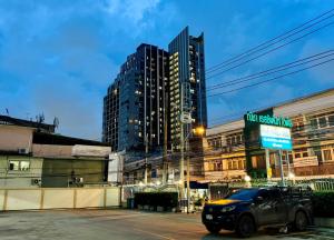 a car parked in a parking lot with tall buildings at Nicha Residence Hotel in Bangkok