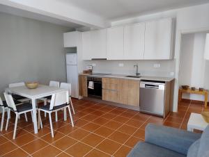 een keuken met witte kasten en een tafel en stoelen bij Bay View Apartments in Albufeira