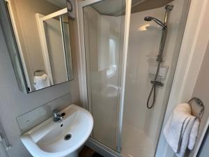 a white bathroom with a shower and a sink at 3 Bedroom Caravan MC37, Shanklin, Isle of Wight in Shanklin