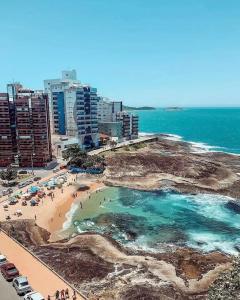 a view of a beach with people and the ocean at Ivana Imoveis - Grupo de Aptos Temporada - Praia do Morro in Guarapari
