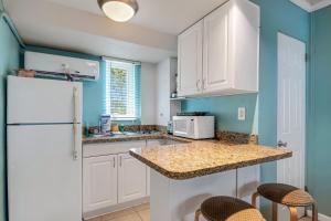 a kitchen with white cabinets and a white refrigerator at Tropic Terrace Suite #4 - Beachfront Resort in St Pete Beach