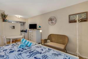 a bedroom with a bed and a chair and a tv at Tropic Terrace Suite #48 - Beachfront Resort in St Pete Beach