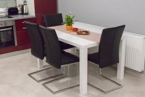 a white table with black chairs in a kitchen at Comfortable four-room apartment in Beli Manastir