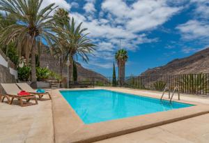 a swimming pool with a bench and palm trees at El Molinero Alto in Mogán