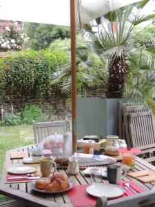 een houten tafel met eten erop bij Chambre d'hôte le jardin de l'Esplanade Rennes Centre et gare in Rennes