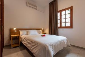 a bedroom with a white bed with a flower on it at La Casa del Molinero in Mogán