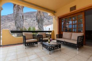 a porch with chairs and a couch and a table at La Casa del Molinero in Mogán