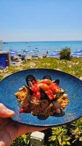 a person holding a plate of food on a beach at Gliù Vico in Formia