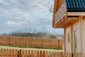 a fence in front of a house with mountains in the background at Villa Boguckowianeczka in Ząb