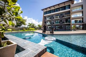 une femme debout devant un bâtiment avec une piscine dans l'établissement Bela Vista Beach by New Time, à Porto de Galinhas