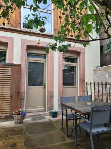 a table and chairs in front of a building with a door at Gîtes Le Séchoir in Saint Die