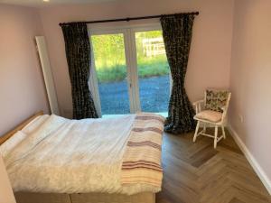 a bedroom with a bed and a window with a chair at 3 bedroom Beautiful Cosy Cottage in Killashandra
