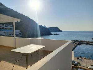a table on a balcony with a view of the water at Porto Anafi in Anafi