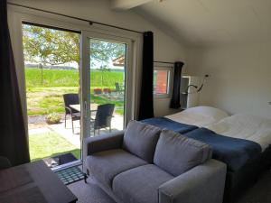 a bedroom with a bed and a couch and a window at Mariafarm Chalets in Zevenbergen