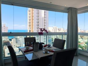 a dining room with a table and a large window at Ivana Imoveis - Vários Aptos de Temporada mesmo Prédio na Praia do Morro in Guarapari