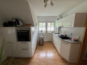 a kitchen with white cabinets and a sink and a window at Susewind in Bad Segeberg