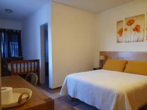 a bedroom with a white bed and a table at APA Las Condalias in Puerto Madryn