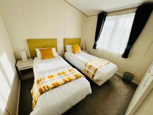 two beds in a small room with a window at 2 Bedroom Lodge, OG30, Shanklin, Isle of Wight in Shanklin +17 photos