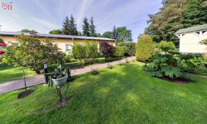 a garden with trees and bushes and a building at Haus Am Wald in Ahlbeck