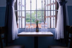 a table with glasses and a vase with flowers in a window at MOJA HOUSE l Homestay Huế in Thôn Dương Xuân Hạ