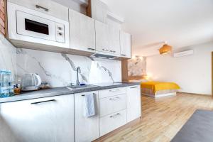 a kitchen with white cabinets and a bed in a room at Apartamenty Grodowa 2 in Gliwice