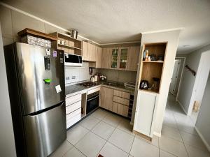 a kitchen with a stainless steel refrigerator and wooden cabinets at Departamento frente a la playa en Los Molles in Los Molles