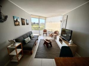 a living room with a couch and a tv at Departamento frente a la playa en Los Molles in Los Molles