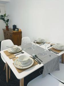 a white table with plates and glasses on it at Bay Wind Apartment in Morecambe +13 photos