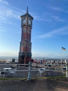 a clock tower with tables and chairs in front of it at Bay Wind Apartment in Morecambe