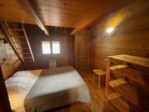 1 dormitorio en una cabaña de madera con cama y escritorio en Chalet Aravis, en Le Grand-Bornand