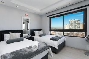 a bedroom with two beds and a large window at Luxury Beachfront 706 with AC, Workspace & Table Mountain Views in Cape Town