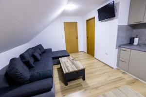 ein Wohnzimmer mit einem schwarzen Sofa und einem Holztisch in der Unterkunft One-bedroom apartment with terrace in Darda