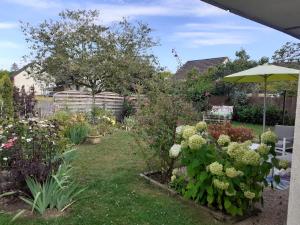 a garden with flowers and an umbrella at Les Oiseaux chambre d'hôtes in Saint-Florent-sur-Cher