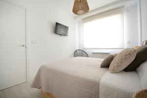 a white bedroom with a bed and a window at GALIHOST - Apartamento en Playa de Compostela in Vilagarcia de Arousa