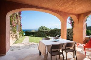 een patio met een tafel en stoelen en een boog bij Sherden suites - Your House in Sardinia in Golfo Aranci