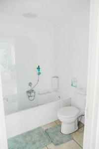 a white bathroom with a toilet and a bath tub at Baydream Away in Cape Town +35 photos