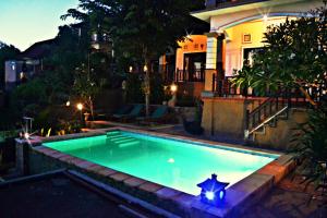 a swimming pool in front of a house at night at Acarya Bungalows Amed in Amed