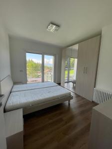 a bedroom with a large bed with a large window at Nuovo appartamento affitto in Cavareno