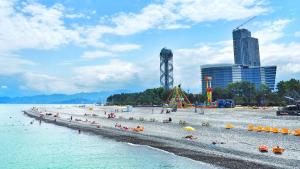 une plage avec un groupe de personnes dans l'eau dans l'établissement Batumi Real Lux, à Batoumi