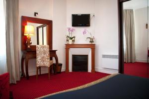 a room with a fireplace and a chair and a mirror at Chez Madame Cailleau in Houlgate