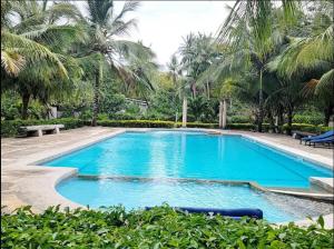 a large blue swimming pool with palm trees at Beach Haven! Cozy Cottage in Mombasa