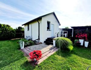 una pequeña casa blanca con flores en un patio en Bursztynek Łunowa, en Świnoujście