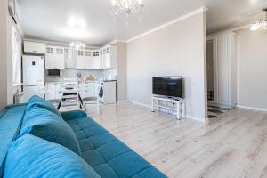 a living room with a blue couch and a kitchen at Kamal Apart in Prigorodnyy