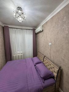 Cette chambre comprend un lit avec des draps violets et un lustre. dans l'établissement Abay street- Tashkent city center, à Tachkent 25 autres photos