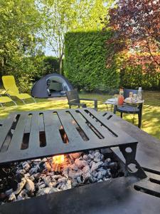 a picnic table with a campfire and a tent at L Escale Nature in Tournai