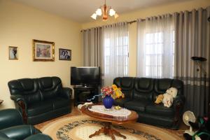 a living room with two black leather couches and a table at Villa Elena Gorice in Berat