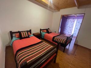 two beds sitting in a room with a window at Casa Solcoy in San Pedro de Atacama
