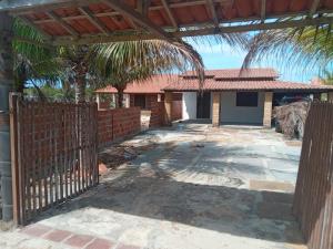 una recinzione di fronte a una casa con una palma di Pousada Recanto do Macapá a Luis Correia